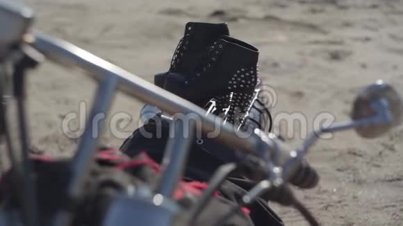 带高跟鞋和黑色和红色连衣裙的加钉鞋躺在摩托车特写上戴着头盔的摩托车视频的预览图