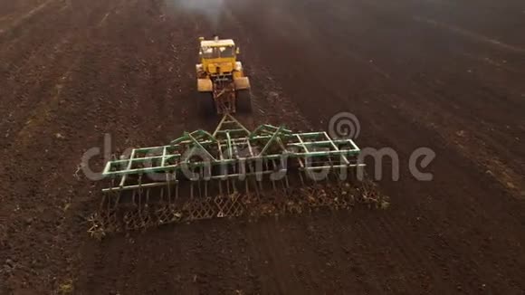 鸟瞰一辆强大的黄色拖拉机花了很大的力气在钩上进行犁耕播种冬季视频的预览图
