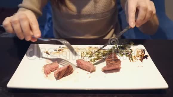 女孩在盘子里切了一块牛排在咖啡馆里吃视频的预览图