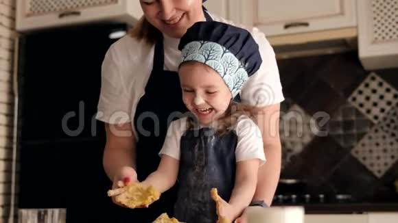 一个戴着帽子和围裙的可爱孩子正在厨房里玩面团视频的预览图