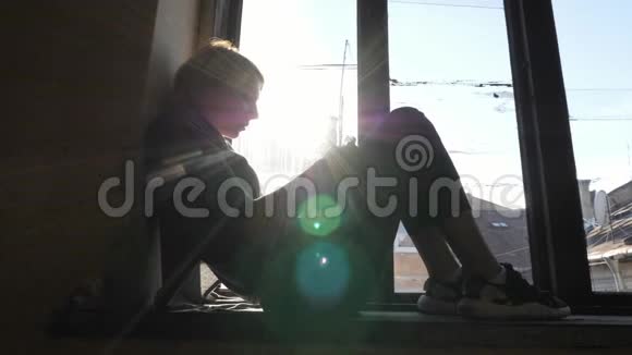 女孩的剪影喝酒坐在窗台上视频的预览图