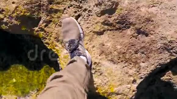 穿棕色运动鞋的人在岩石表面绿色苔藓水坑石头在水坑里倒影阳光明媚的日子散步视频的预览图