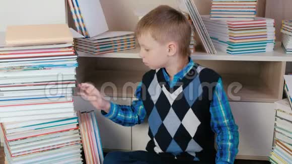 七岁的男孩把书从书堆里拿出来坐在书间看书视频的预览图