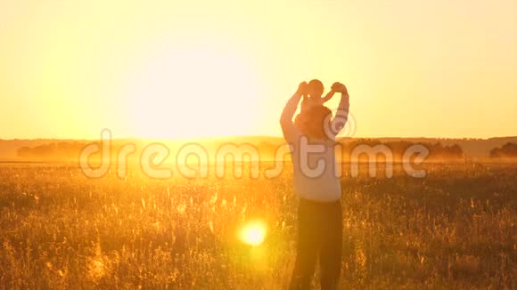 快乐的爸爸熊宝宝坐在他的肩膀上在夕阳下的金色阳光和笑声慢动作视频的预览图