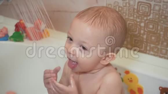 可爱的小男孩洗澡和冲洗浴缸里的小孩带着五颜六色的玩具在浴室里微笑的孩子婴儿视频的预览图