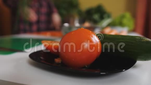西红柿和黄瓜在厨房桌子上的盘子上女人在厨房准备蔬菜沙拉视频的预览图