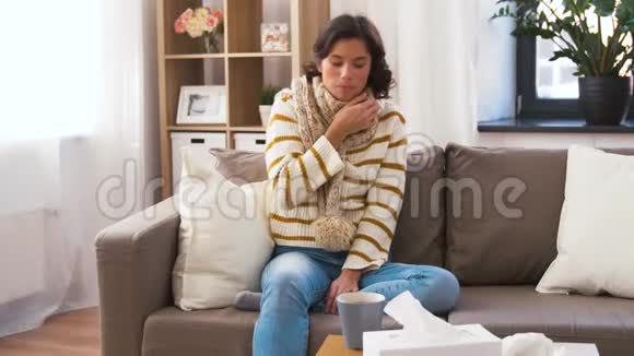戴着围巾的病青妇在家喝热茶视频的预览图