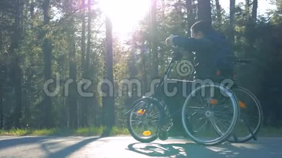 一个残疾男子坐在训练轮椅上的森林小巷视频的预览图
