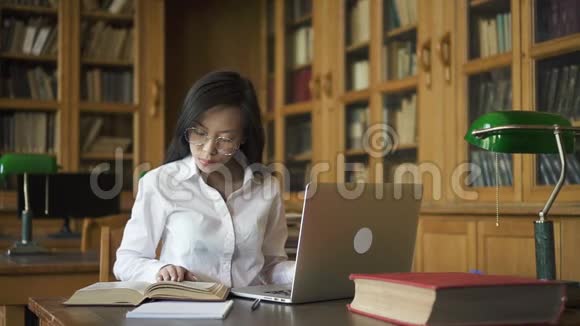 戴着绿灯坐在桌子旁的亚洲女学生视频的预览图