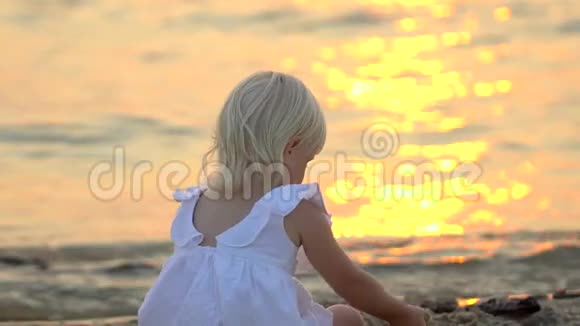 在美丽的夕阳下孩子坐在沙滩上悠闲地享受着快乐的假期在水里玩得开心的孩子视频的预览图