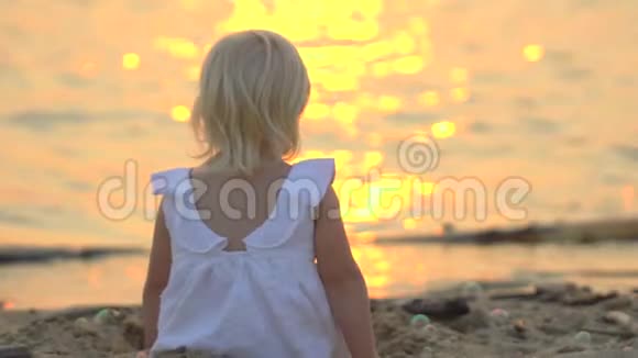 在美丽的夕阳下孩子坐在沙滩上悠闲地享受着快乐的假期在水里玩得开心的孩子视频的预览图