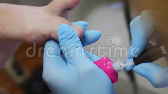 美容师用粉色皮肤紫胶在美容院涂脚趾甲视频的预览图
