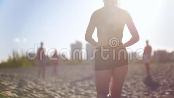 年轻漂亮苗条的女孩带着排球跑向朋友们还有沙滩排球比赛视频的预览图