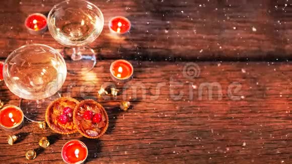 蜡烛和两个玻璃杯放在木头上再加上降雪视频的预览图