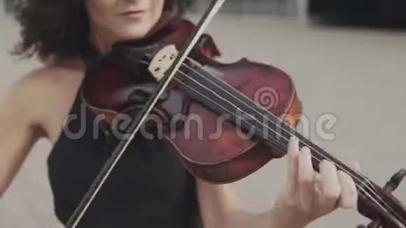 在玻璃大厦附近一位身穿黑色礼服的漂亮小提琴手视频的预览图