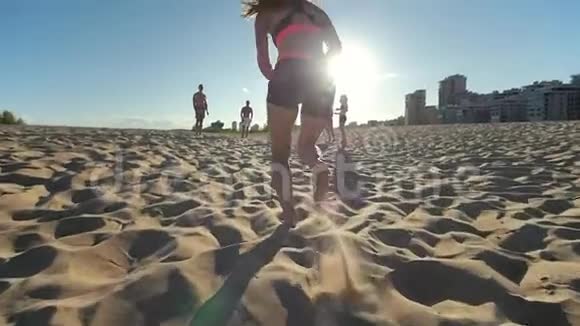 瘦小的运动女孩在沙滩上奔跑停下来把球传给朋友沙滩排球视频的预览图