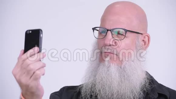 一个成熟秃头满脸笑容的男人用电话视频的预览图
