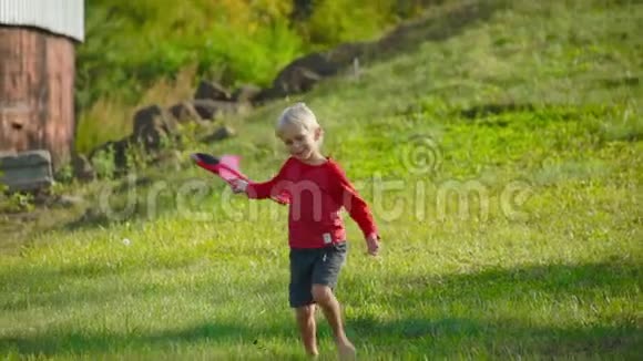 一个小男孩在草坪上玩飞机的慢镜头视频的预览图