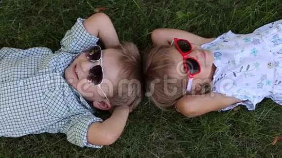 两个戴墨镜的小朋友趴在草地上头对头视频的预览图
