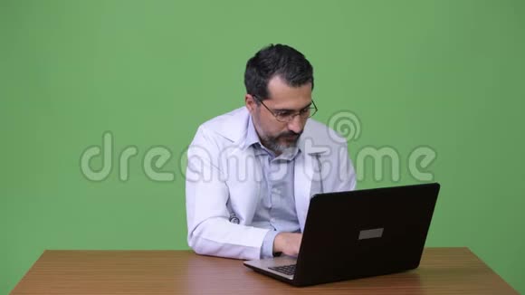 英俊的波斯胡子男医生手提电脑和问候视频的预览图