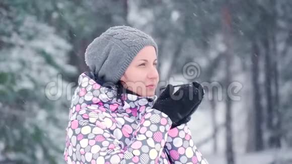 一个女孩站在寒冷的森林或公园里在一个下雪的冬天一位女游客从杯子里喝热茶旅游业和旅游业视频的预览图
