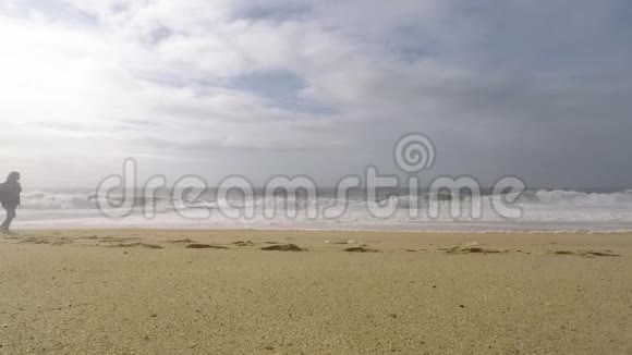 一位年轻女子正在葡萄牙拿撒勒的北海滩上散步视频的预览图