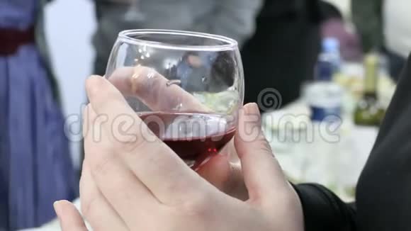 女人拿着一杯红酒在这次活动中人们把杯子和饮料粘在一起4K超高清超高清视频的预览图