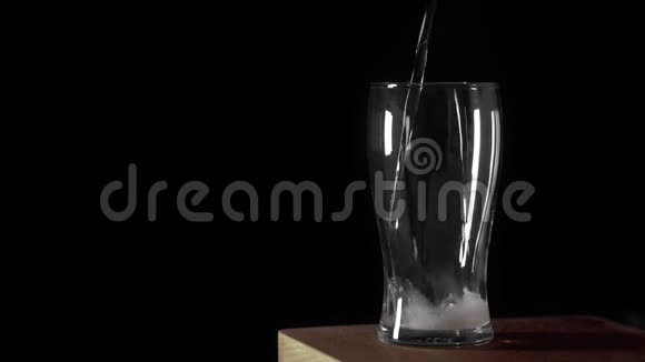 冷光啤酒倒入一个玻璃与水滴始终哑光黑色背景边框设计手工啤酒凑近了视频的预览图