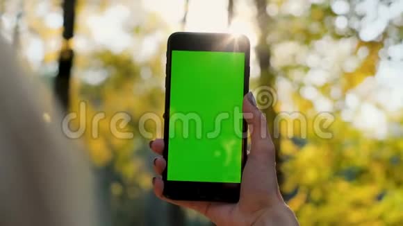 女孩显示手机绿色屏幕户外城市环境女士手拿智能手机与色度键关门视频的预览图