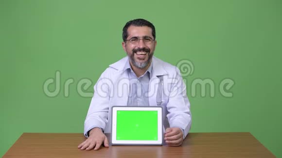 英俊的波斯胡子男医生一边竖起大拇指一边显示数字平板电脑视频的预览图
