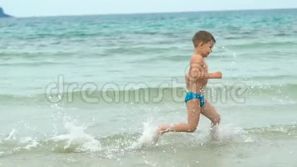 快乐的小男孩在热带海滩沿着海边奔跑视频的预览图