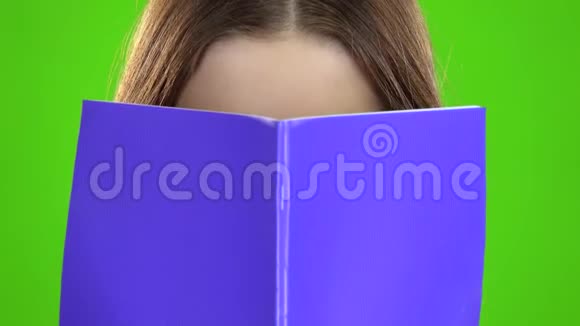 女学生用紫色的笔记本遮住了她的脸绿色屏幕关门视频的预览图