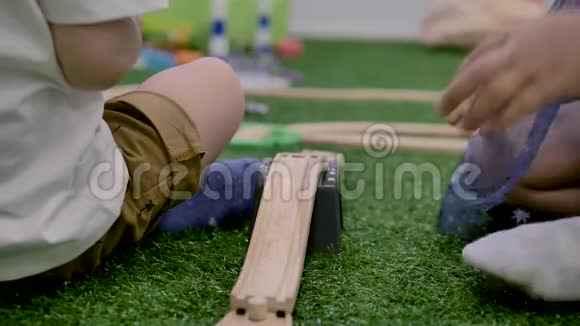 男孩和女孩玩塑料玩具坐在房间里的绿色人造草地上视频的预览图