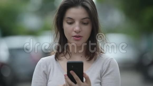 年轻的美女在户外的街道上使用电话时看上去很震惊视频的预览图