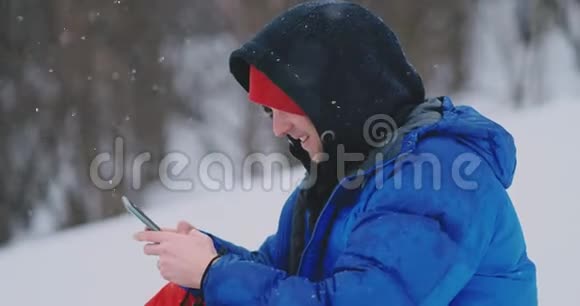 男性滑雪者坐在雪地上拍照打电话美丽的风景胜地为社交网络服务视频的预览图