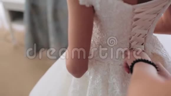 早安新娘伴娘在婚纱上系蝴蝶结女人双手在新娘的胸衣上系绸带帮助视频的预览图