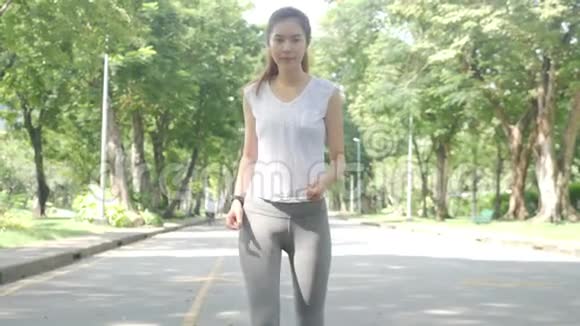 年轻迷人的女人在绿色城市公园跑步锻炼户外健身跟踪可穿戴技术视频的预览图