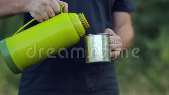 男人手把热水瓶里的热茶倒进杯子里视频的预览图
