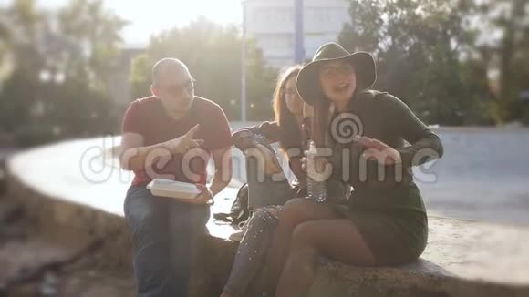 日落时分一群朋友在城市街道上喝瓶装水吃薯条视频的预览图
