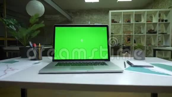 特写笔记本电脑绿色屏幕放在白色桌子上室内现代化的光线荒芜的办公室视频的预览图
