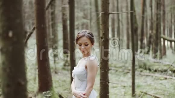 美丽的新娘的肖像婚礼的花束矗立在松林的苔藓上视频的预览图