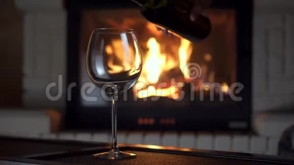 在背景的玻璃酒杯壁炉里从瓶子里倒入溅满红酒的全镜头视频的预览图