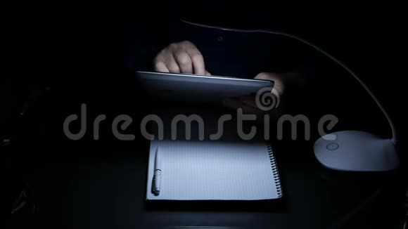 商人在黑暗的办公室里用电子平板电脑发短信视频的预览图