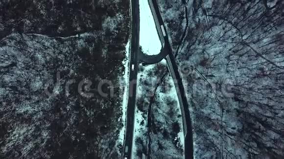 在雪林中驾驶冬季乡村道路的汽车从无人驾驶飞机上俯瞰空中景色视频的预览图