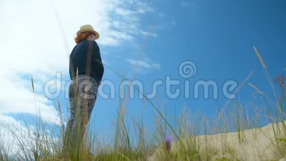 远望未来的女人站在沙滩上天空的背景视频的预览图