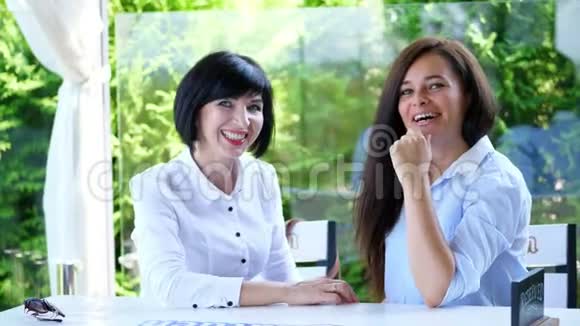 夏天在一家咖啡馆的露台上两个四十岁的漂亮黑发女人正在聊天她们很可爱视频的预览图