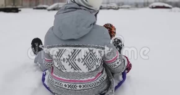 妈妈在冬天拉雪橇和孩子们在白雪上后景视频的预览图