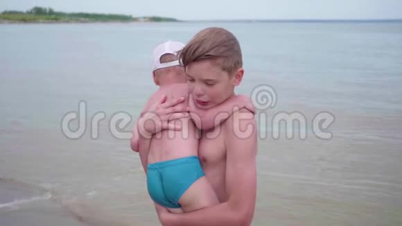 哥哥在海滩上和一个孩子玩他抱着一个孩子视频的预览图