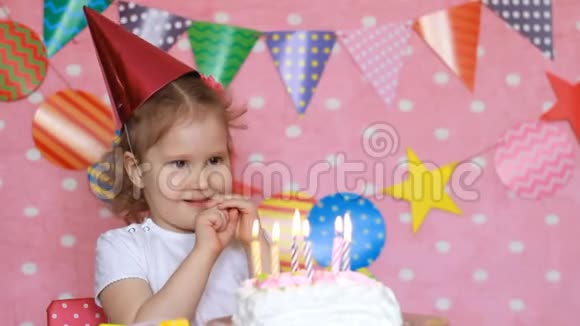 装饰生日和装饰可爱的小女孩和带蜡烛的蛋糕孩子们假期快乐的孩子粉色视频的预览图