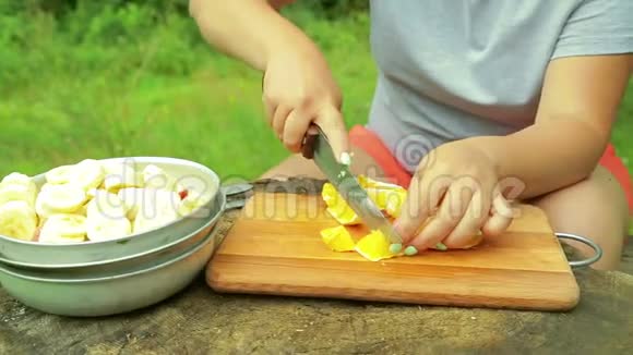 在野餐时女性用手在木板上切一个新鲜的水果橘子片作为沙拉视频的预览图